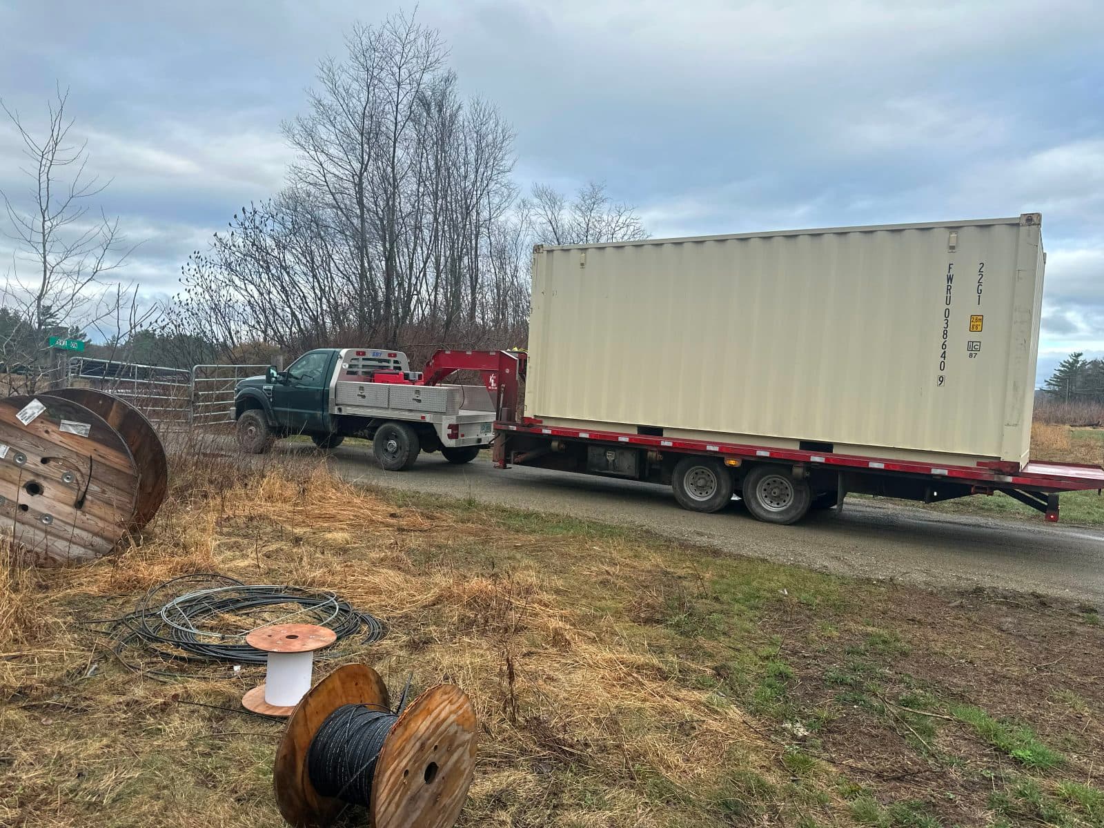Container delivery truck parked along a rural gravel road
