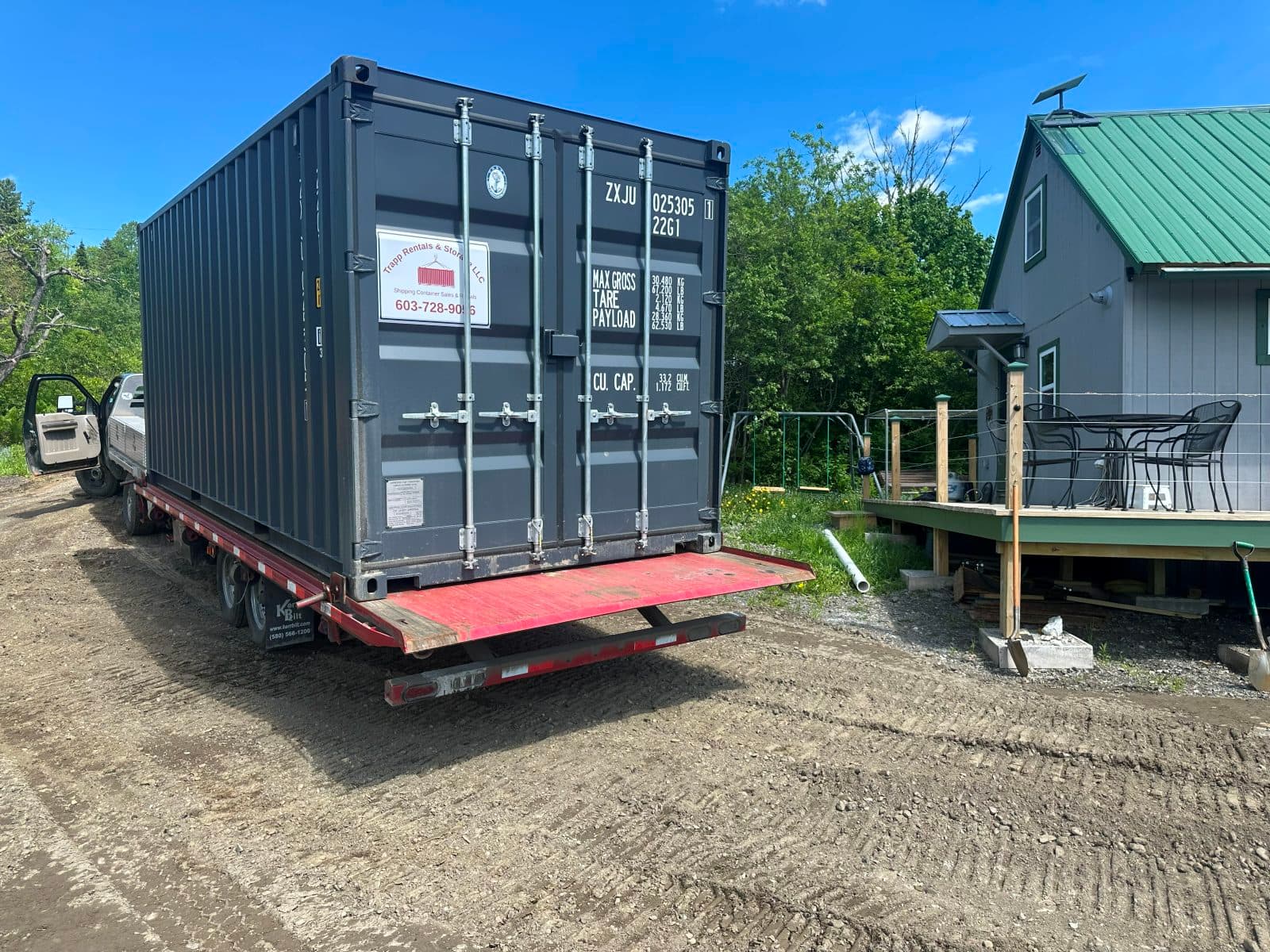 Shipping container delivered up a dirt driveway to a rural home