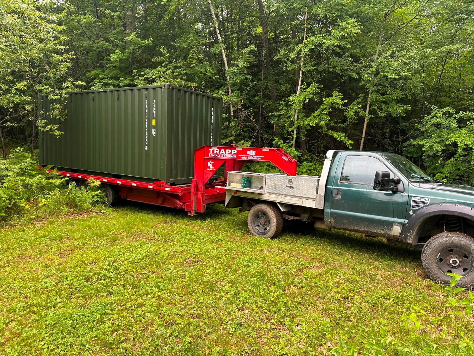 Container delivered into a grass clearing surrounded by woods